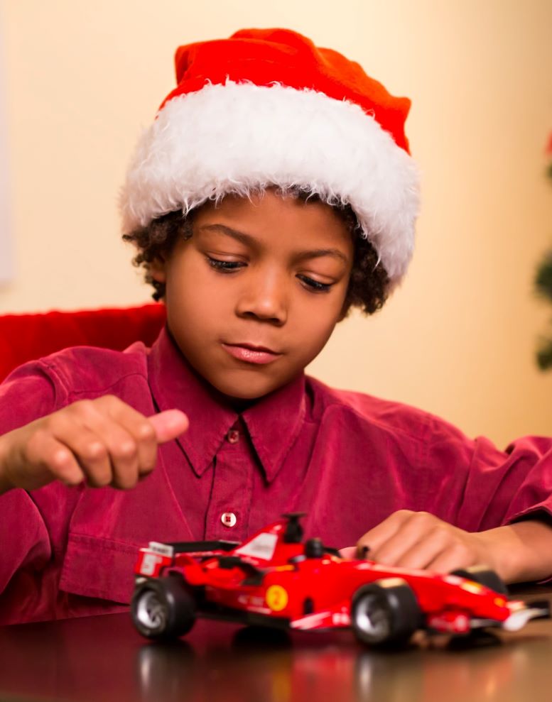 Boy wearing Santa hat playing with toy car