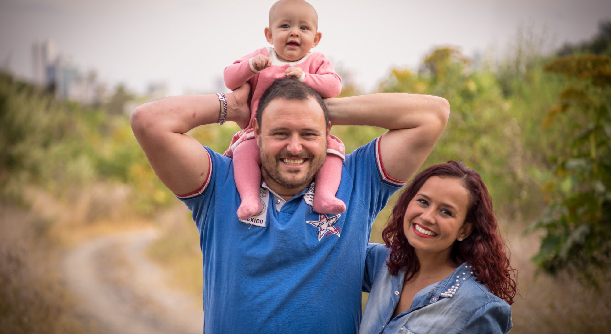 family mom dad and infant walking on a dirt path