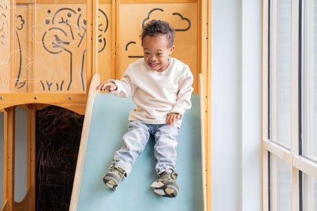 child with down syndrome on playground slide